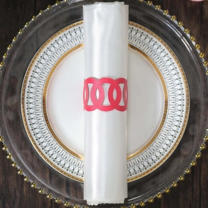 Detail of red hollowed-out napkin ring with interlocking circles on a white napkin