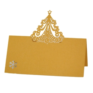 Detail of laser-cut golden Christmas tree and snowflake patterns on pearlescent table card
