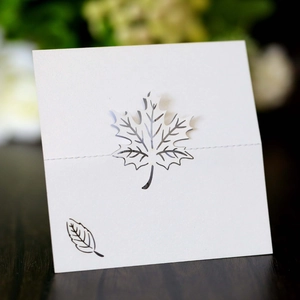 Detail of laser-cut maple leaf hollow design on white paper place card for table setting