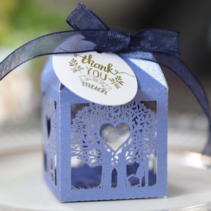 Close-up of laser-cut tree candy box with blue chiffon ribbon and thank you tag