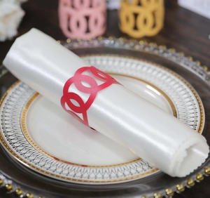 Detail view of red laser-cut paper napkin rings with hollow interlocking design for weddings