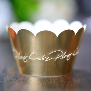 Vista macro de la envoltura dorada para cupcake con elegante texto Play Cake Play
