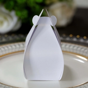 Close-up of elegant white laser-cut wedding favor box with tulip design on ceramic plate