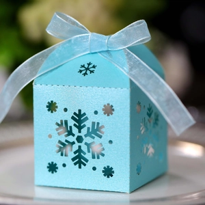 Primer plano de caja para dulces azul claro con copos de nieve calados y lazo de cinta