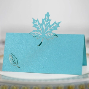Macro shot of laser-cut teal maple leaf place card with pearlescent finish and texture