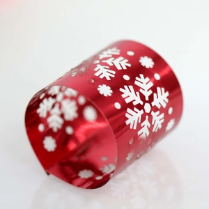 Close-up of a festive red metal napkin ring with laser-cut snowflake patterns and dots