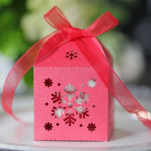 Detalle de caja rosa para dulces con copos de nieve calados y lazo de cinta de seda
