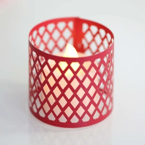 Detail of red hollowed-out paper lampshade with warm LED candle light inside