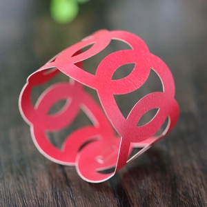 Close-up of red hollow laser-cut paper napkin ring with interlaced circular patterns