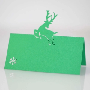 Detail of green laser-cut reindeer and snowflake Christmas place card on mirror surface