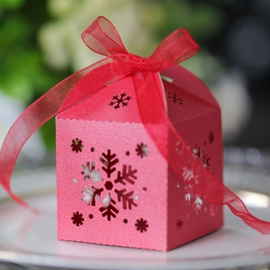 Caja de regalo roja cortada con láser con copos de nieve y cinta sobre un plato blanco