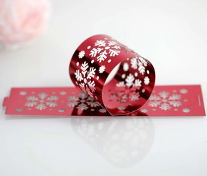 Close-up of laser-cut red snowflake napkin rings with metallic finish for holiday decor