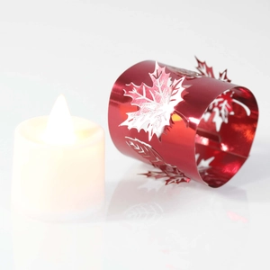 Macro view of laser-cut maple leaf red metal ring with a white LED tealight candle