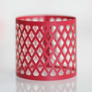 Close-up of red hollow laser-cut paper candle holder sleeve with diamond grid pattern