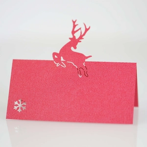 Laser-cut red Christmas place card featuring a reindeer and snowflake on kraft paper