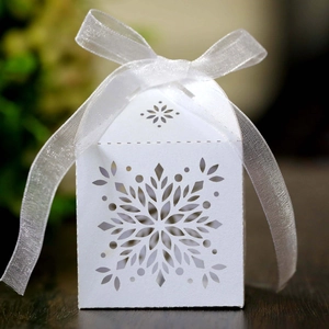 Detailed laser-cut snowflake paper candy box with white organza ribbon for parties