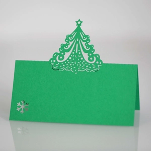 Detail of laser-cut green Christmas tree place card with hollow snowflake on cardstock