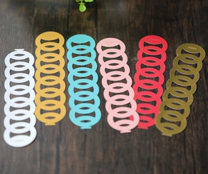 Detailed view of six hollowed golden and colorful napkin ring bands on dark wood