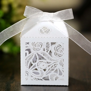 Detail of laser-cut rose hollow pattern on white wedding favor box with silk ribbon