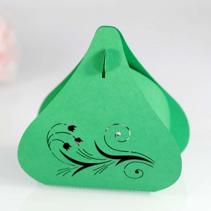 Close-up of green laser-cut wedding favor box with intricate floral vine patterns