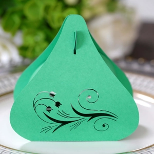 Green laser cut tulip wedding favor box on white porcelain plate with floral background