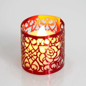 Dettaglio del copricandela rosso traforato a rose con candela LED a luce gialla