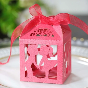Boîte à dragées rose découpée au laser avec silhouette de couple et ruban en satin rouge