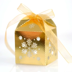 Detalle de caja dorada para dulces con patrones de copos de nieve y lazo de cinta de organza