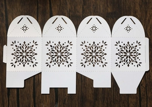 Macro view of white snowflake laser-cut paper candy box flat sheet on dark wood