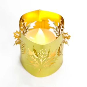 Macro detail of golden metal hollow maple leaf candle holder with warm LED light