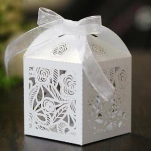 Close-up of laser-cut white rose favor box with an elegant white organza ribbon bow