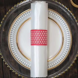 Detail of red hollowed-out lattice napkin ring on white napkin on decorative dinner plate
