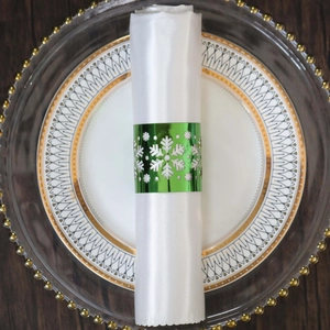 Close-up of a green snowflake napkin ring on a white napkin over luxury tableware