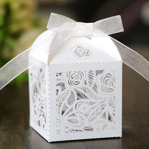 Close-up of white laser-cut hollow floral candy box with a white organza ribbon bow