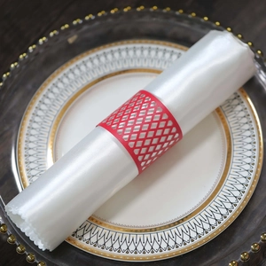 Detailed view of red laser-cut diamond mesh napkin ring on a white elegant dinner plate