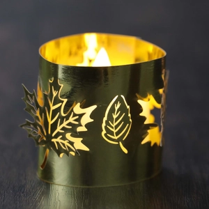 Detail showing a golden maple leaf cutout metal lantern with a glowing warm candle