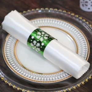 Detailed view of emerald green snowflake napkin ring on elegant white dinner plate