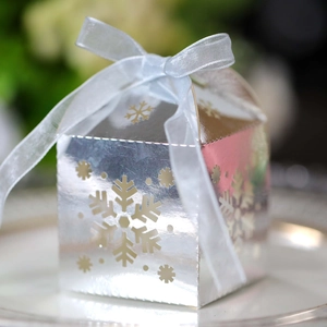 Primer plano de caja de regalo plateada con copos de nieve y lazo azul claro