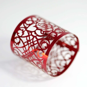 Dettaglio ravvicinato di un anello decorativo in metallo rosso con rose tagliate al laser