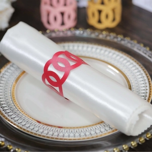 Elegant red geometric hollowed napkin ring on a white silk napkin for banquet table decor