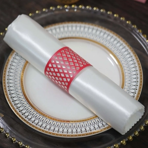 Detail shot of a red laser-cut hollow napkin ring with elegant white satin cloth on porcelain