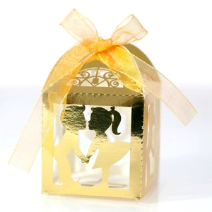 Détail boîte cadeau mariage dorée découpée au laser avec silhouette couple et ruban élégant