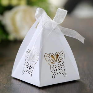 Detail of white pyramid favor box featuring laser-cut butterfly and silk ribbon bow