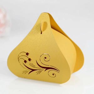 Macro shot of laser-cut tulip patterns on golden pearlescent paper candy box gift