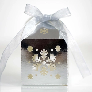 Detalle de caja para dulces plateada con recorte de copo de nieve y lazo de cinta