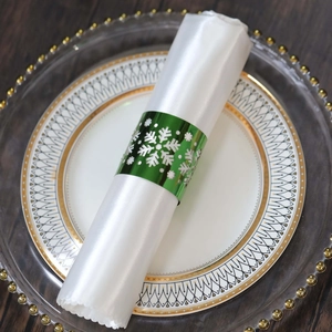 Macro detail of glossy green metal napkin ring with snowflake pattern on white satin