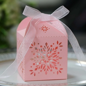 Close-up of pink laser-cut snowflake candy box with elegant white organza ribbon bow