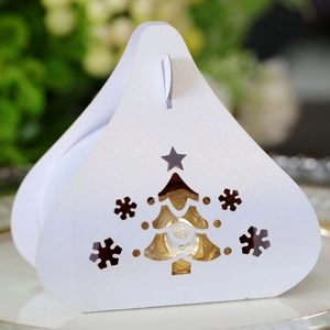Macro shot of white laser-cut Christmas tree and snowflake details on a candy gift box