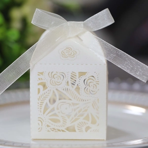 Detail of white laser-cut wedding candy box with rose patterns and white organza ribbon