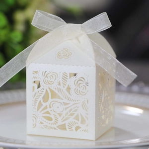 Macro view of laser-cut rose patterns on pearlescent cream-white wedding favor boxes